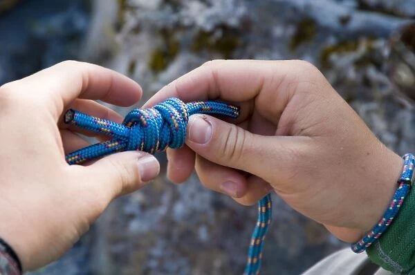 New Zealand, South Island. NOLS student tying a Double Fishermans knot