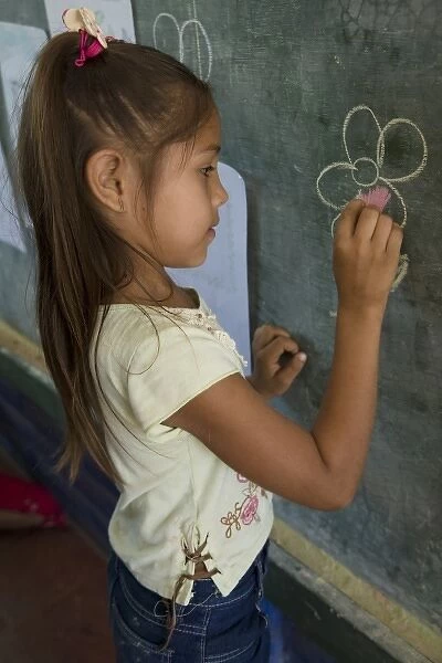 Nicaragua, Granada. Girl writing on blackboard in school classroom in Santa Ana de Malacos