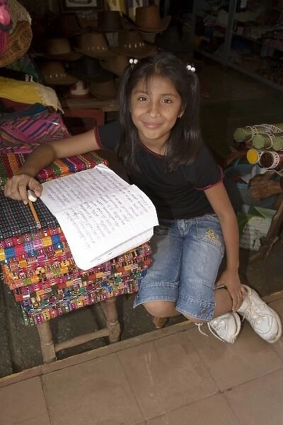 Nicaragua, Masaya. Girl doing schoolwork at shop in Masaya market
