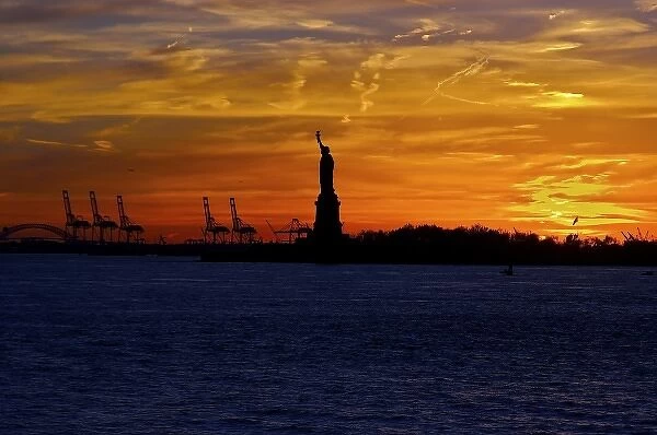 North America, USA, New York, New York City. The Statue of Liberty in silhouette at sunset