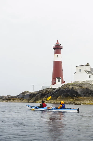 Norway, Nordland. Suzanne Spencer and Dylan McGuire sea kayaking past Trany light house