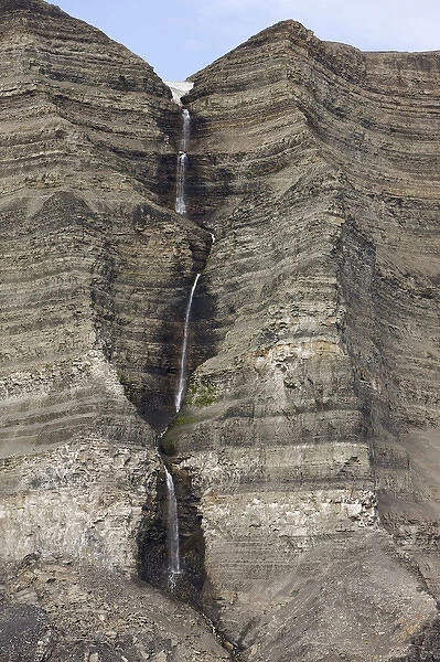 Norway, Svalbard, Edgeoya Island, Waterfall on steep cliffs of Kualpyntfjeller Mountain