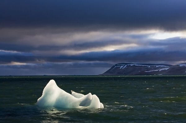 Norway, Svalbard, Nordaustlandet, Setting sun lights iceberg floating in Palanderbukta
