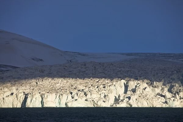 Norway, Svalbard, Nordaustlandet, Setting sun lights ice face of tidewater glacier