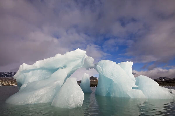 Norway, Svalbard, Spitsbergen Island, Morning sun lights arched iceberg floating