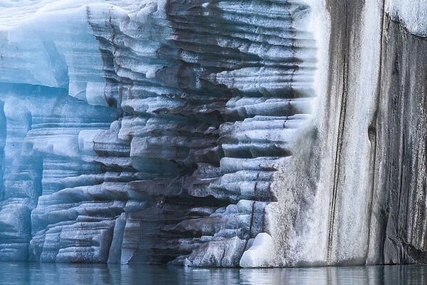 Norway, Svalbard, Spitsbergen. Large piece of glacial ice flipped over with moraine remnants