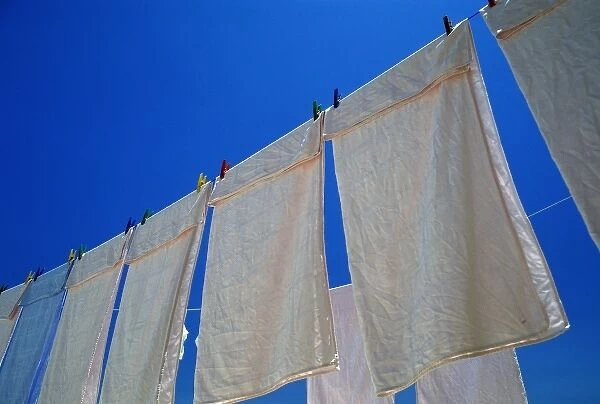 Oia, Santorini, Greece, White linens drying on a clothesline against the blue sky