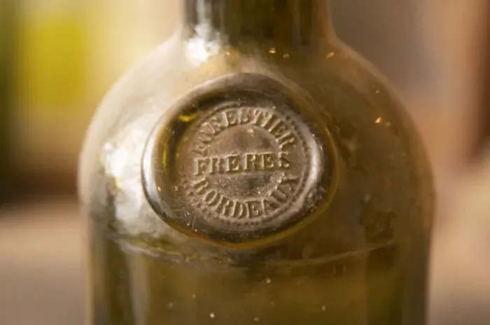 Framed Print : An old antique dusty wine bottle with a moulded seal on the shoulder of the bottle