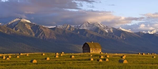 Old barn framed by hay bales and dramatic Mission Mountain Range in Montana