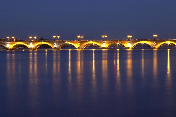 The old Pont de Pierre bridgeat night with reflections in Bordeaux on the Garonne River