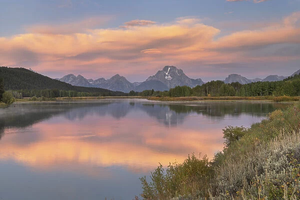 Orange clouds and Mount Moran reflected in still waters of the Snake River at Oxbow Bend at sunrise, Grand Teton National Park, Wyoming