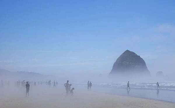Oregon, Cannon Beach. Haystack Rock, beachgoers in fog