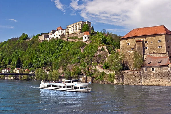 Passau, Germany, a tourist boat sails down the Danube River in front of Veste Oberhaus castle