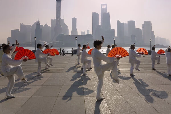 People practicing Taiji with red fans on the Bund in the morning, Pudong skyline
