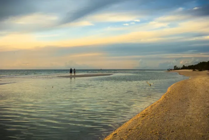 Framed Print : People standing on a sandbar in the water watching sunset