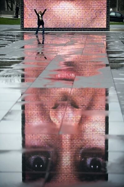 A photo of the Crown Fountain reflecting in puddles from recent rain in Chicago s
