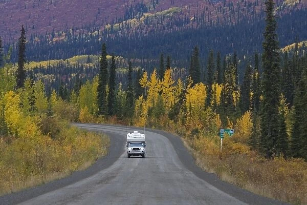 Pickup camper on Dempster Highway in fall; a gravel road between Dawson City
