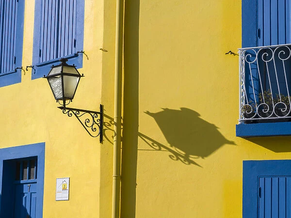 Portugal, Aveiro. Shadow of street lantern on colorful yellow building with bright blue