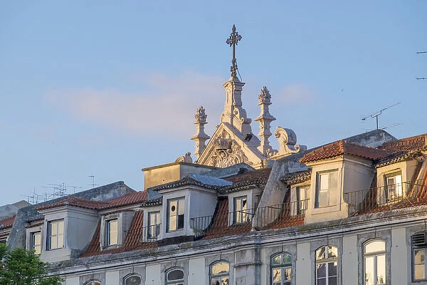 Portugal, Lisbon. Church spire looms out from behind apartment buildings at sunset