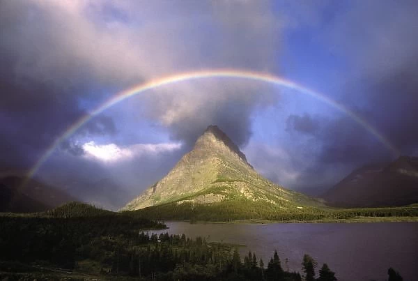 Full rainbow and stormy sky over Grinnell Point and Swift Current Lake in Glacier National Park