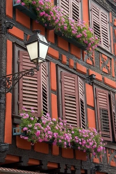 Red building with shuttered windows and flower boxes in the village of Ribeauville, Eastern France
