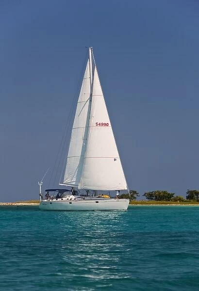 A sail boat sailing by Laughing Bird Cay in Belize