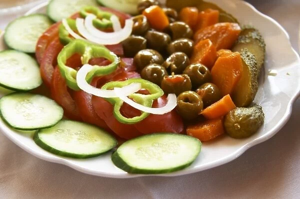 Salad with tomatoes, onions, green bell peppers, cucumbers, cornichons olives and carrots
