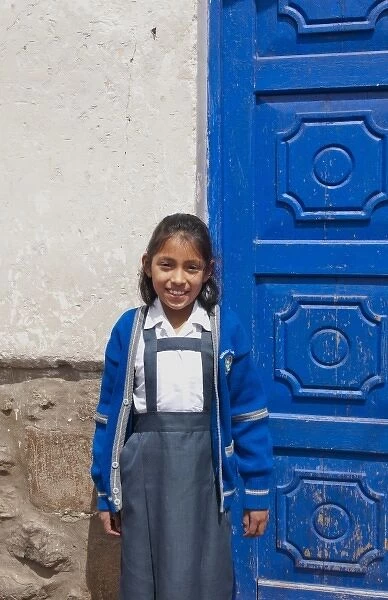 School child aged 10 in uniform and blue door in small town of Pisaq Peru (MR)