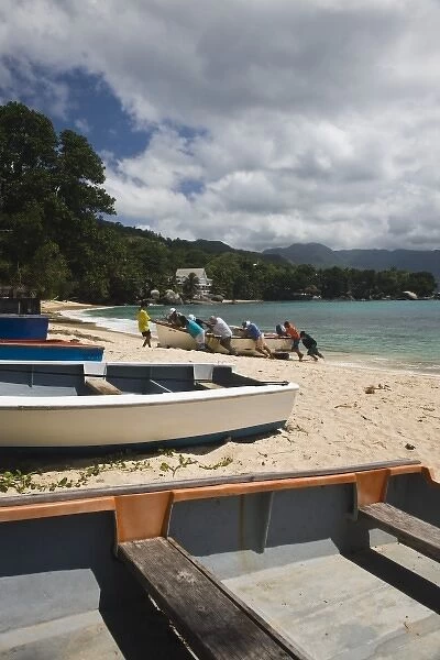 Seychelles, Mahe Island, Baie Beau Vallon, fishermen pulling boat on beach