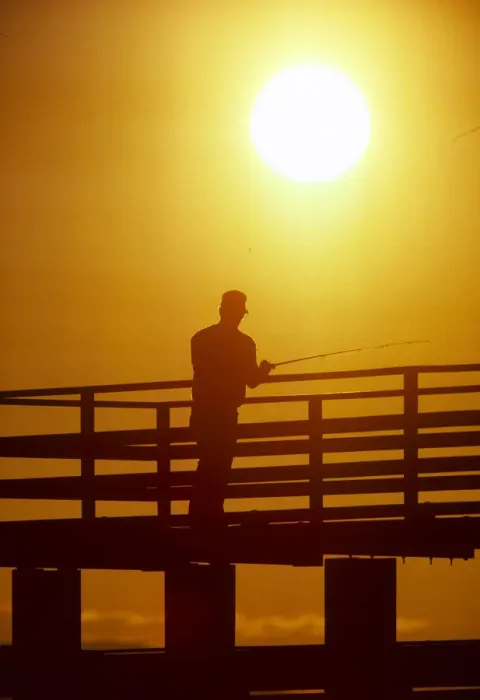 Framed Print : Silhouette of man fishing from a pier