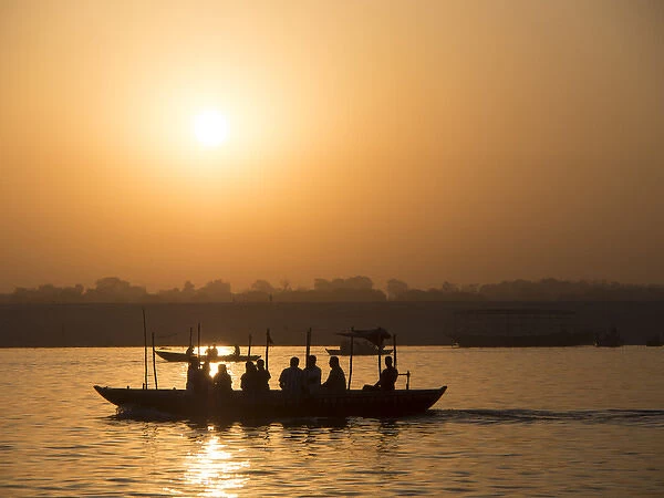 Silhouette of passengers on boat over river during sunrise in Varanasi, Uttar Pradesh