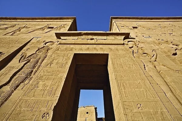 Skyward view of entry pylons and giant figures, Temple of Philae, on Agilika, an