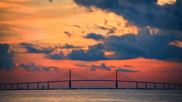The Skyway Bridge over the Gulf of Mexico with the reds and oranges of the sunrise in the sky