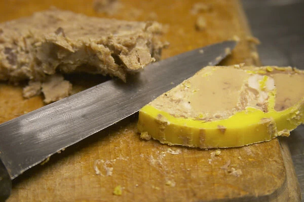 A slice of duck liver foie gras ond a cutting knife on a wooden cutting board Ferme de Biorne duck