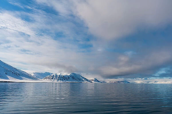 Snow covered mountains rise near the shore of Mushamna Bay. Spitsbergen Island, Svalbard, Norway