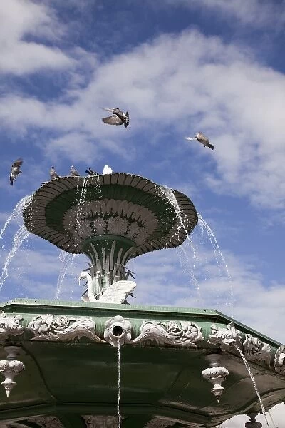 South America, Peru, Cuzco. Birds fly around the fountain in the center of the square