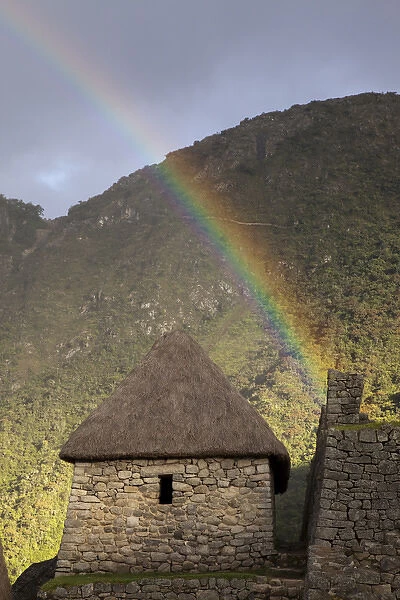 South America, Peru, Machu Picchu. Rainbow over a thatched stone hut at sunset