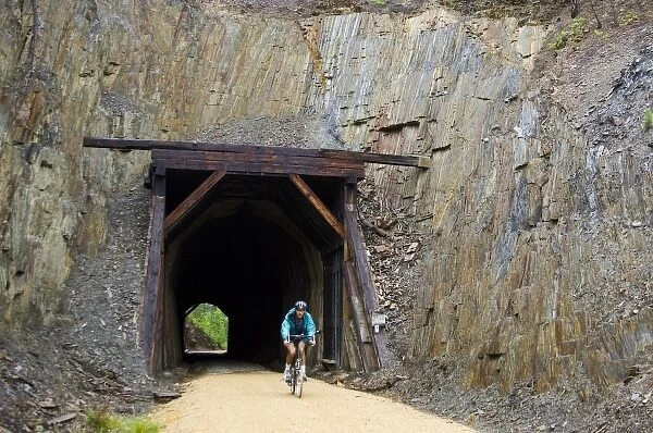 South Dakota. USA. Bicyclist & tunnel through slate along George S. Mickelson Trail