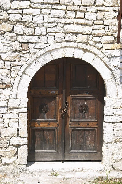 Stone wall with old wooden door with chain and pad lock. Berat upper citadel old walled city