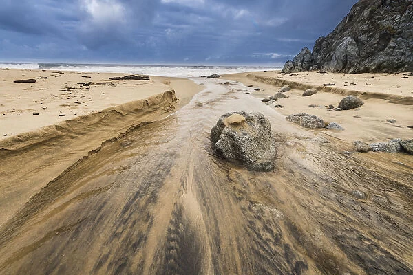 Stream flowing over a rock into the Pacific Ocean at Garrapata Beach, California