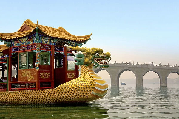 The Summer Palace, Beijing, China, a traditional Dragon Boat passes the Seventeen