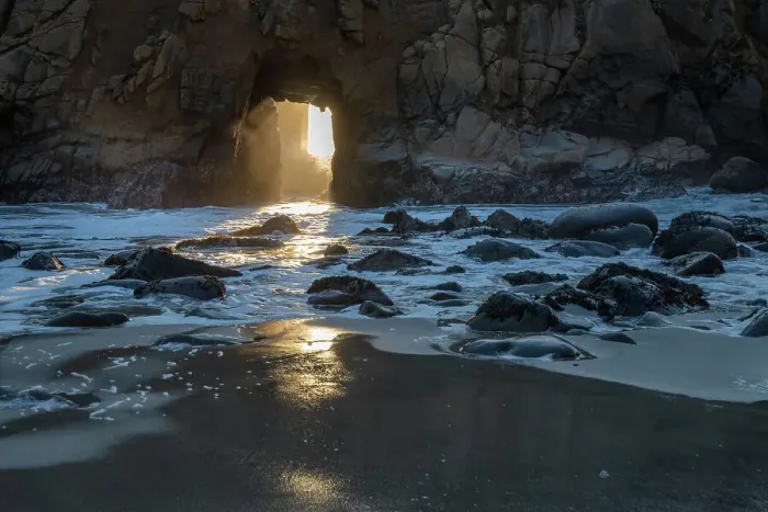 Framed Print : Sun shines through a tunnel in a sea cliff in the Big Sur area