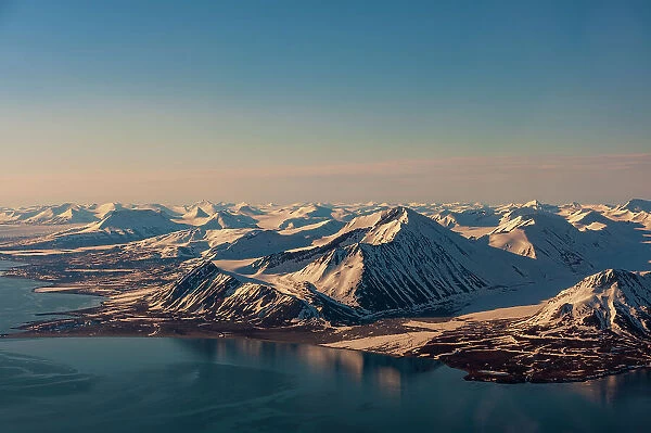 Sunlight highlights ice covered mountains on Spitsbergen Island, Svalbard, Norway