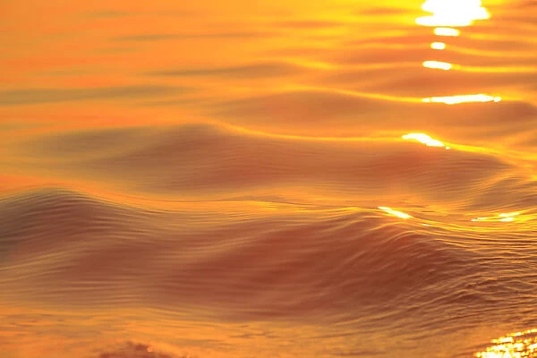 Sunset colors and patterns on small waves in water