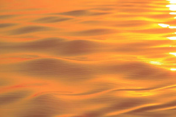 Sunset colors and patterns on small waves in water