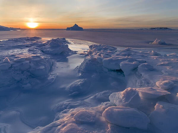 Sunset at the shore of frozen Disko Bay during winter, West Greenland, Denmark