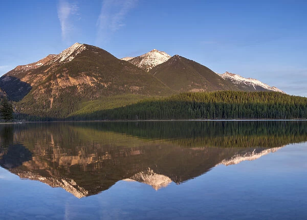 Swan Mountains reflect into calm Holland Lake at sunset in the Lolo National Forest