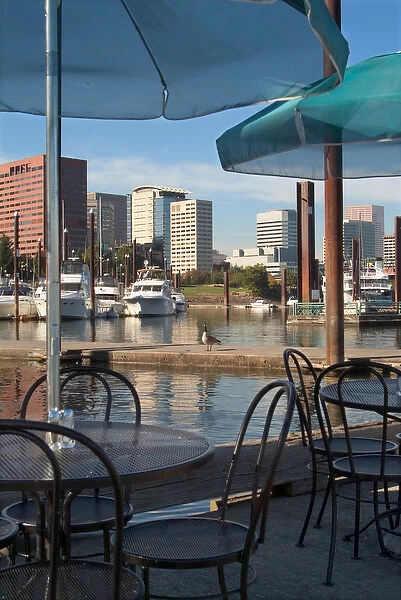 Tables with green umbrellas at a restaurant on the Willamette River, with the Portland Marina