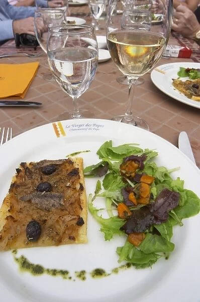 A tarte fine d oignon - onion tart with salad and a glass of water and white chateauneuf