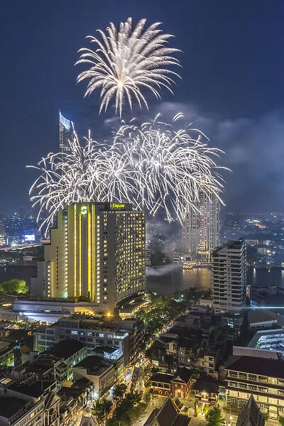 Thailand, Bangkok. Riverside, high angle skyline view with fireworks at dusk